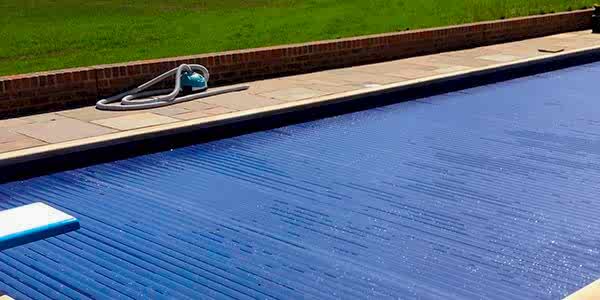 Newly installed semi-automatic retro-fit swimming pool cover on a refurbished kidney shaped swimming pool