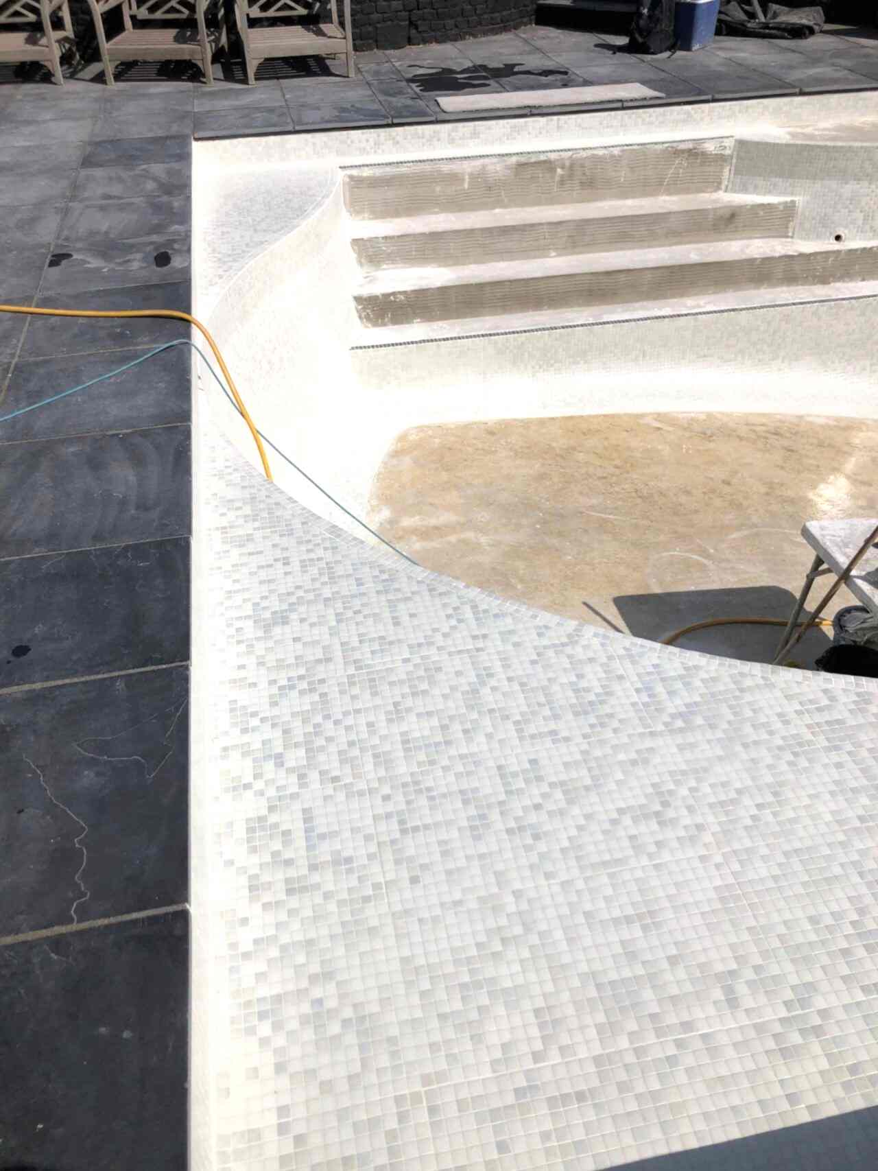 The entire pool interior was retiled with contemporary white glass mosaics and contrasting step demarcations