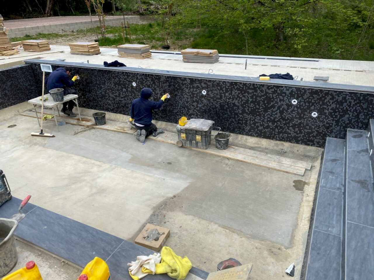 The team of UK Swimming Pools is finishing tiling around the water drain holes