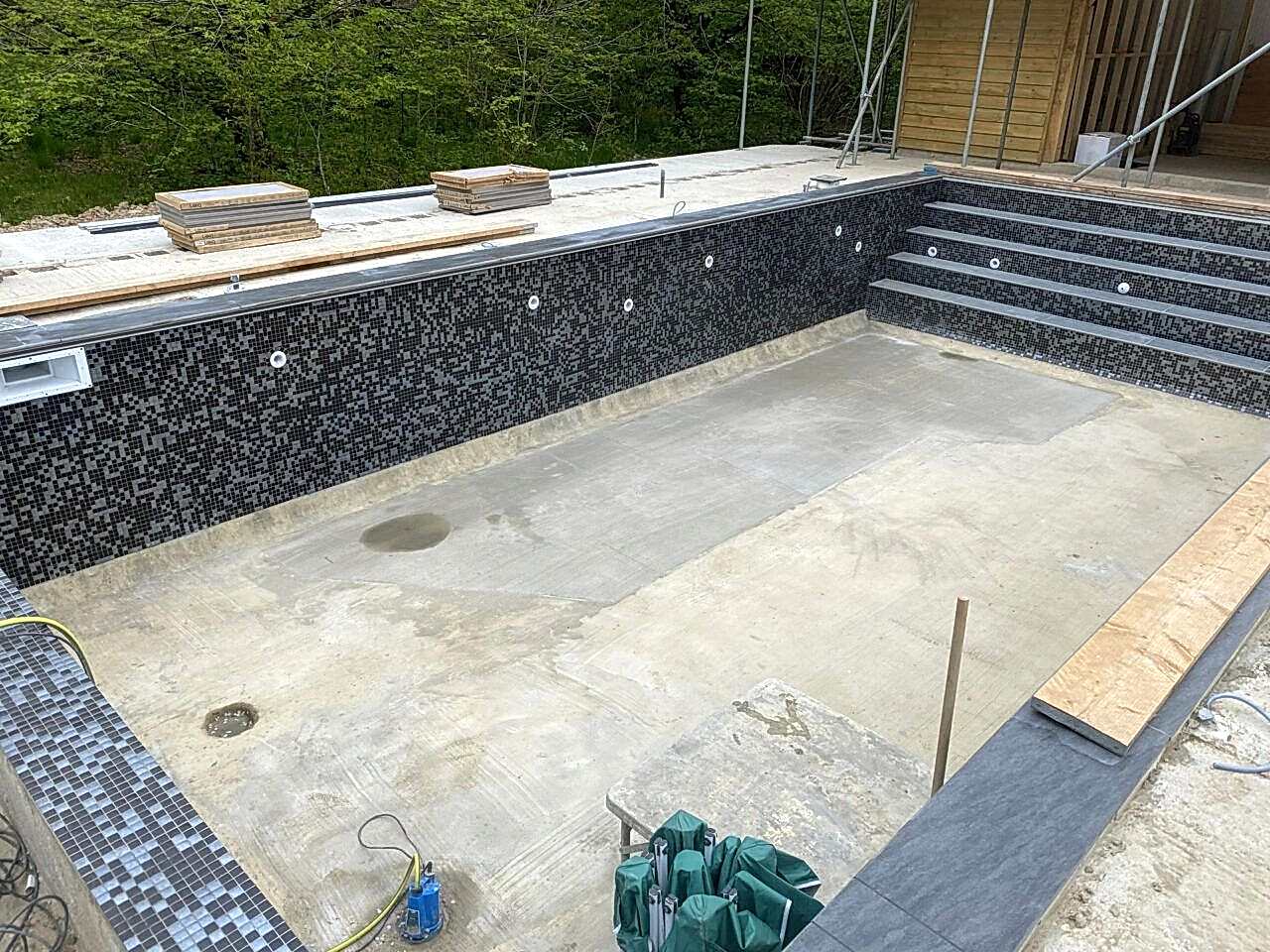 The bottom of the swimming pool is cleaned and ready for the new black and silver mosaic tiles