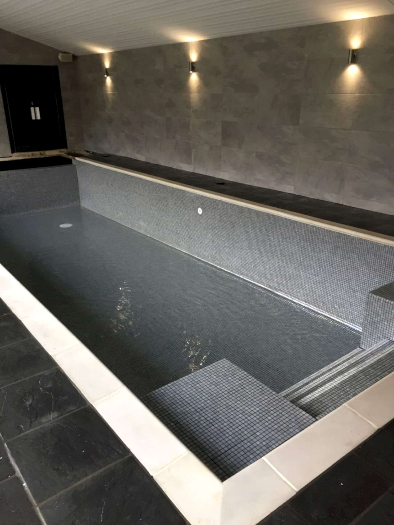 The cover was finished in a sleek grey, further enhancing the overall aesthetic appeal of the iridescent grey mosaic tiled swimming pool