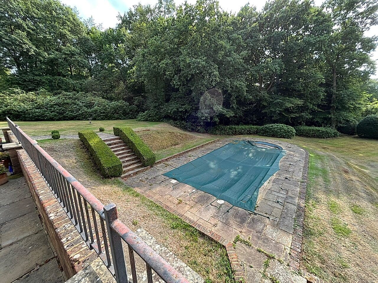 Original frost damaged swimming pool with a manual pool cover before refurbishment started