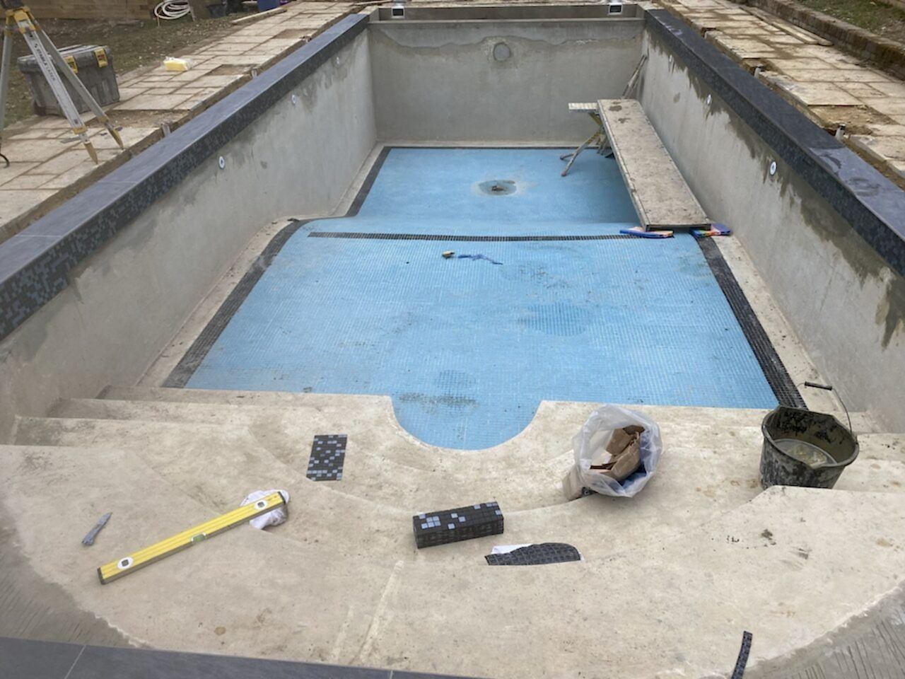 Installing a new mosaic tiled band to the refurbished swimming pool
