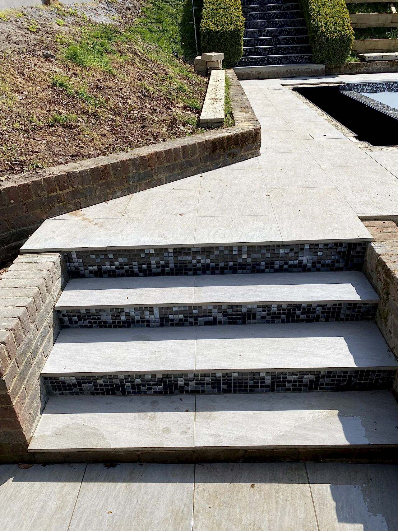 Newly constructed patio steps leading up to the refurbished swimming pool from the garden