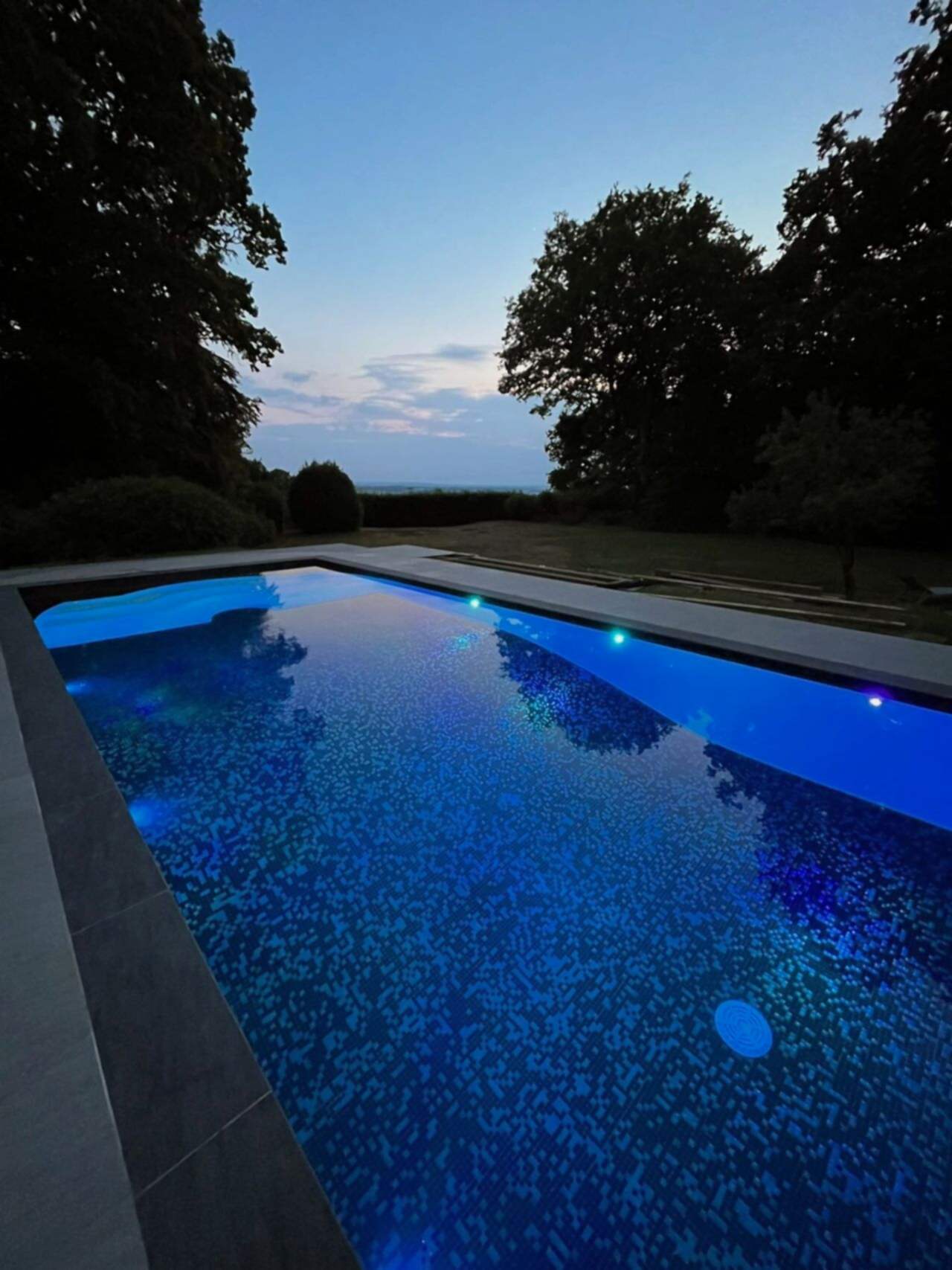 Night time photo of this stunning swimming pool refurbishment with ambient lighting