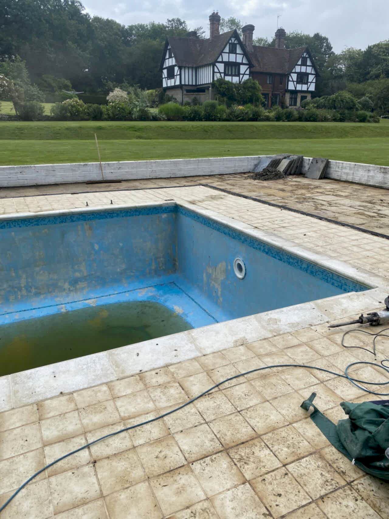 The old paving being removed and the pool drained before retiling