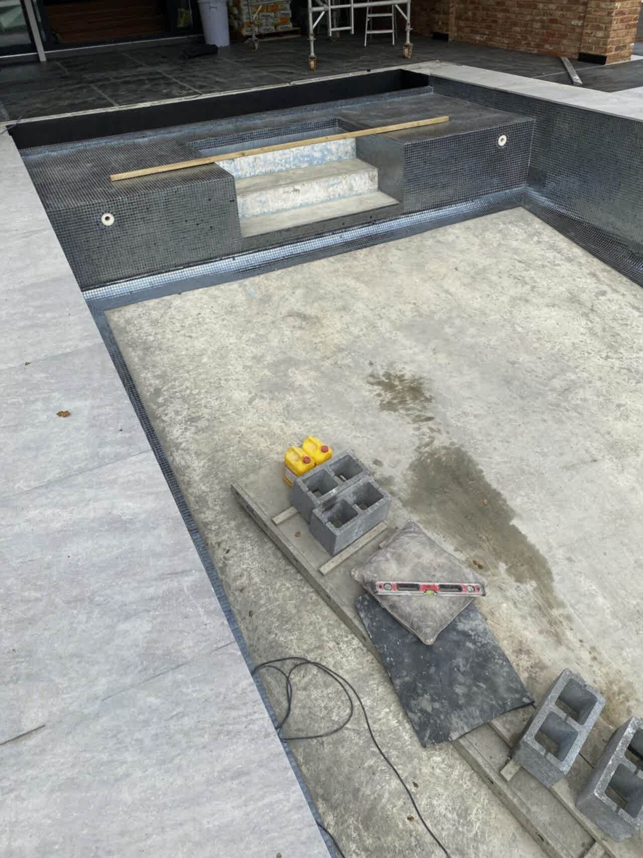 The tiling of the swimming pool continues down from the steps, around the sides of the pool