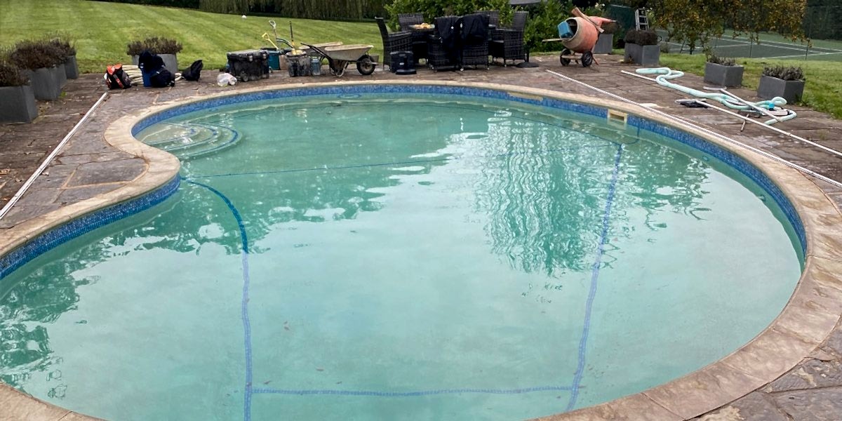 Outdated kidney shaped concrete swimming pool