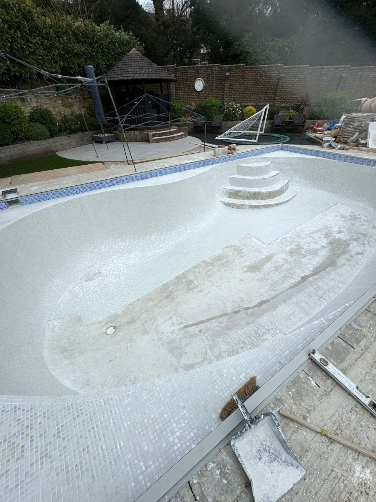 A full view of the new swimming pool. The sides are finished, installation of the Ibiza 23.5mm iridescent glass mosaics on the bottom of the pool is in progress