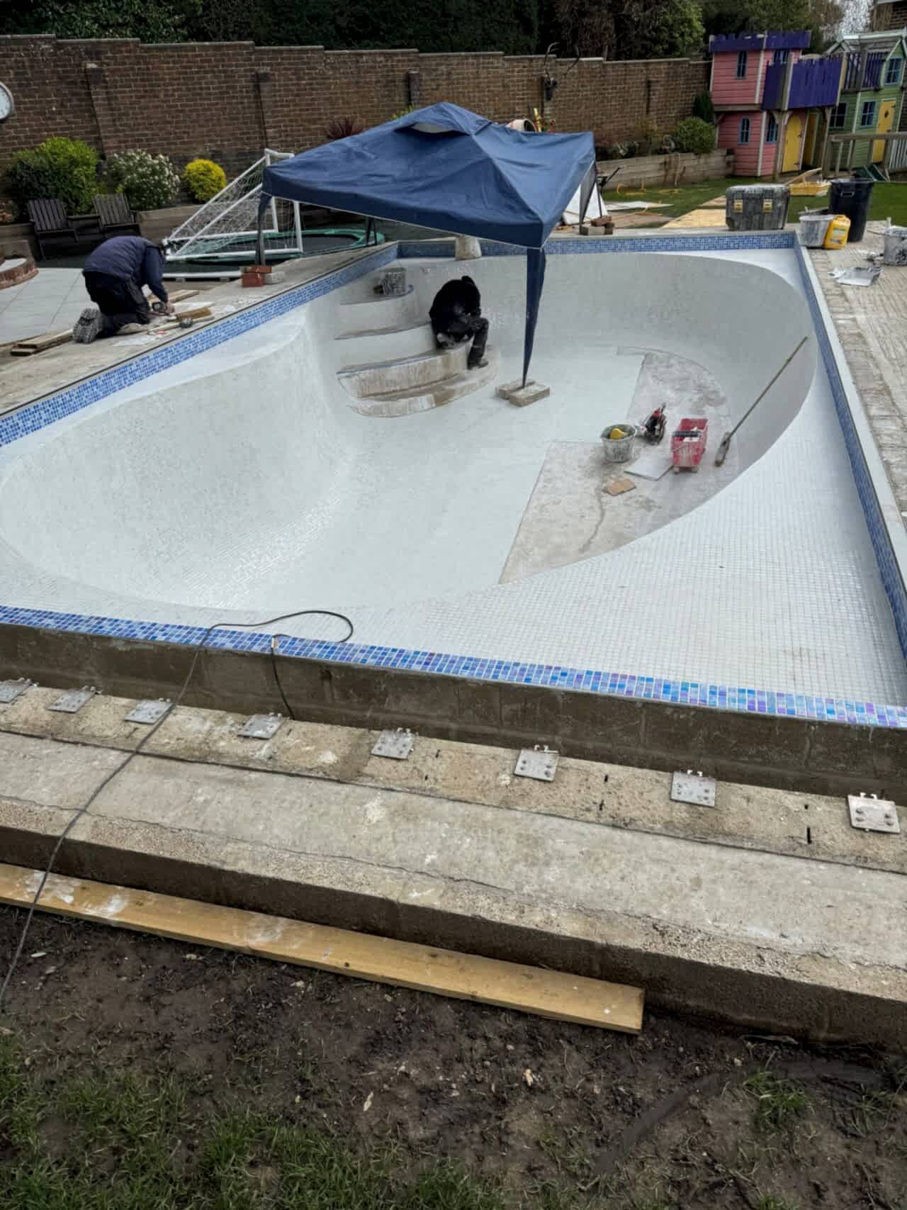 The UK Swimming Pool Team installing the Ibiza 23.5mm iridescent glass mosaics