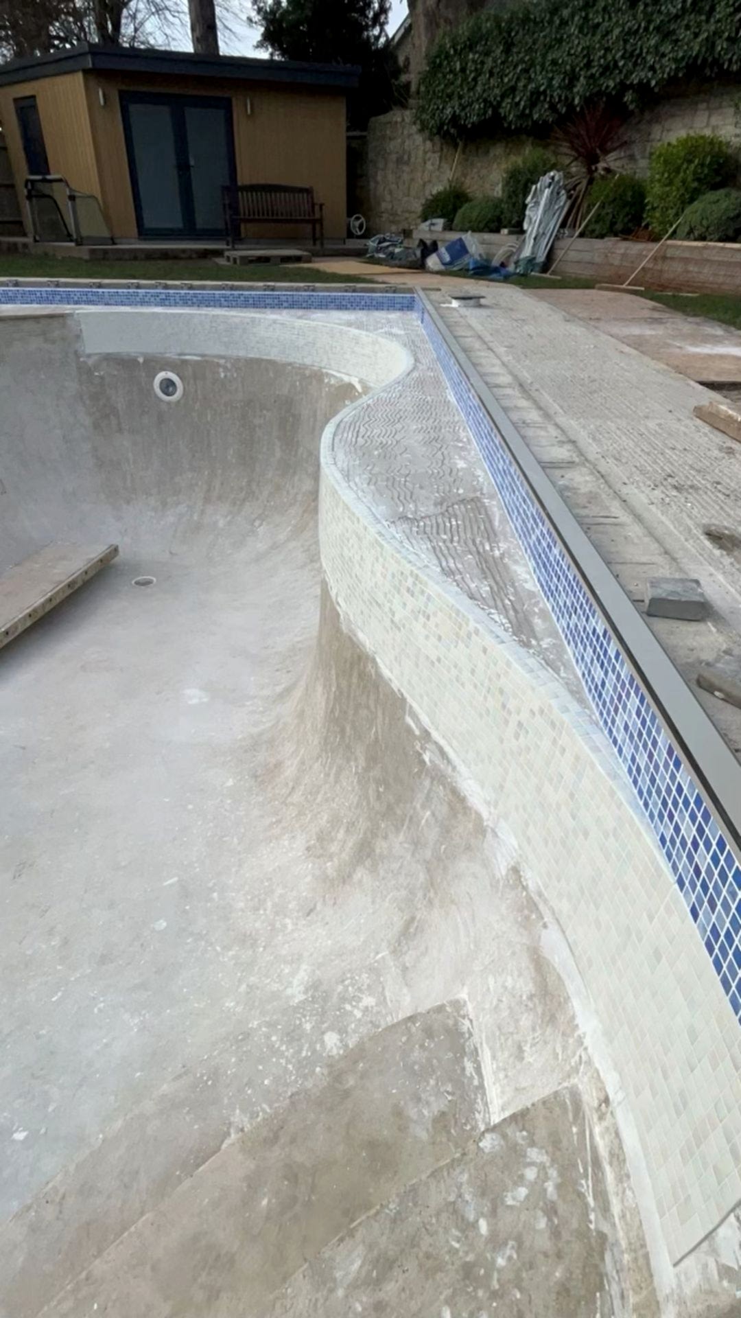 View of the side of the swimming pool showing the Ibiza iridescent glass mosaics and the sky blue tiles for the waterline