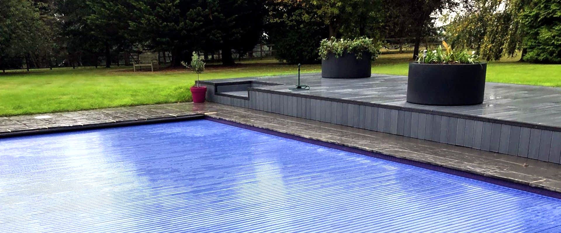 Newly installed semi-automatic retro-fit swimming pool cover on a refurbished kidney shaped swimming pool